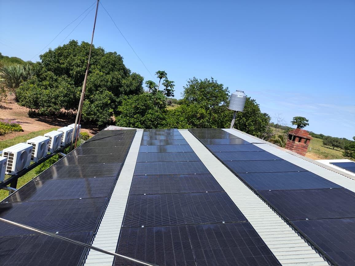 Solarmodule auf dem Dach einer Estancia, daneben Klimaanlagen und Wassertank